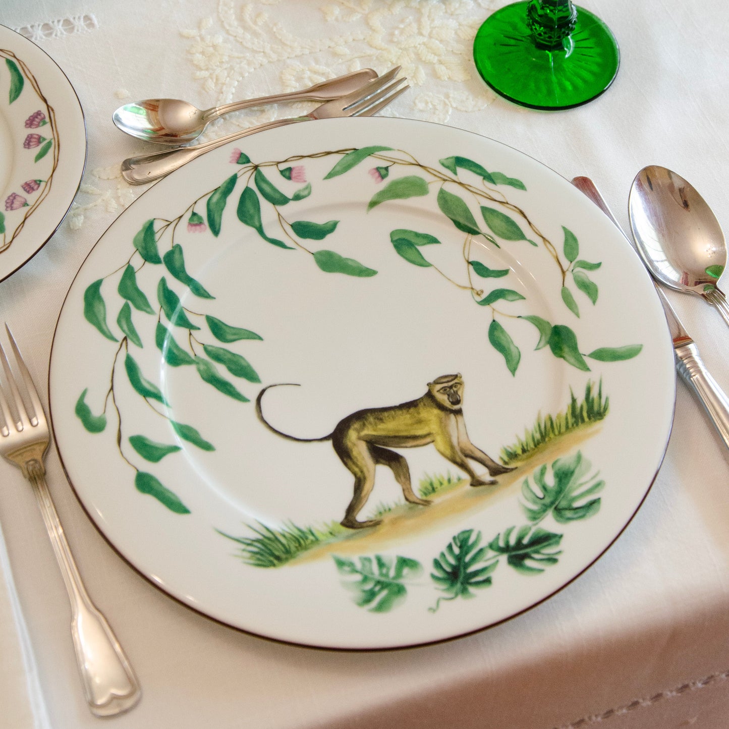 Table setting with decorative plates featuring lion illustrations and green glasses.